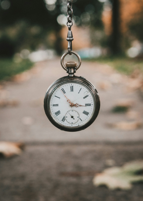 Une montre à gousset tenue par la chaîne dans un parc à l'automne