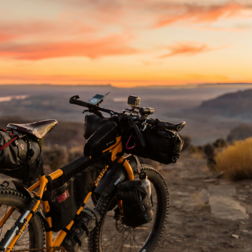 Un vélo arrêté sur une montagne faisant face à un coucher de soleil 