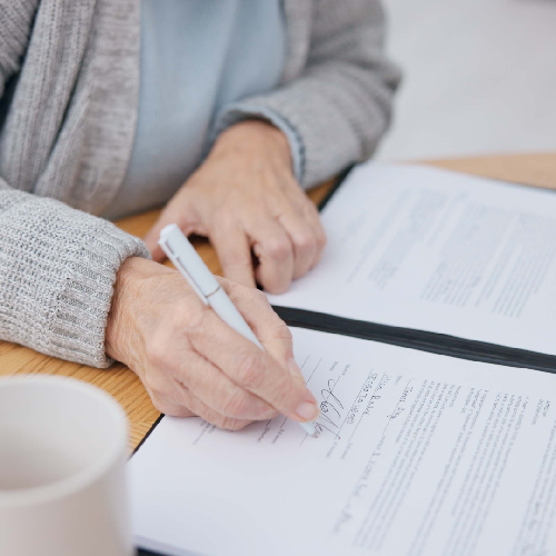 Une personne écrit dans un cahier avec un stylo.